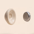 The Magnetic Soap Holder, a cream ceramic disc shown with a small metal disc